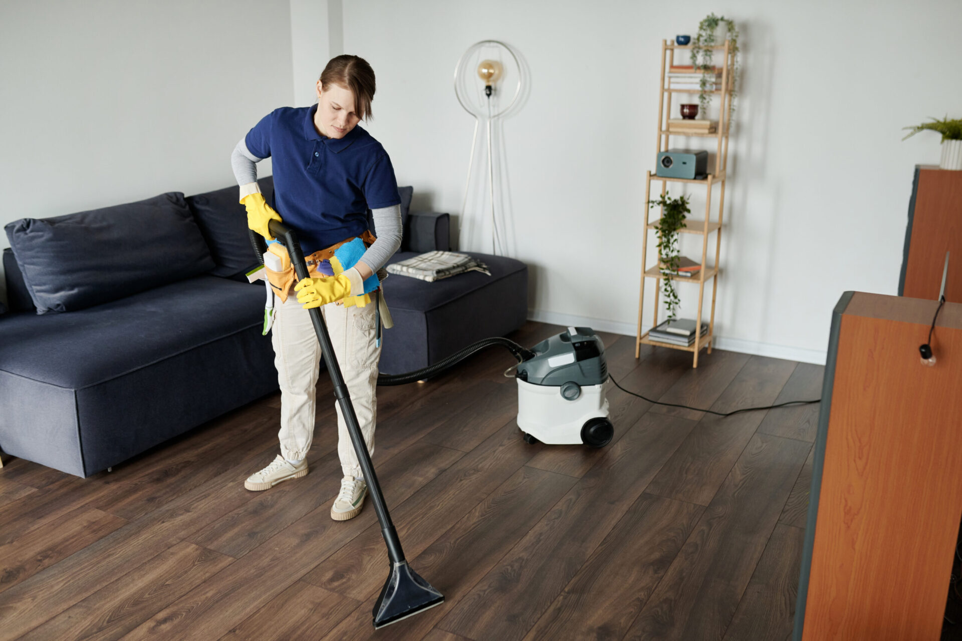 Professional cleaning service worker vacuuming the floor in the room