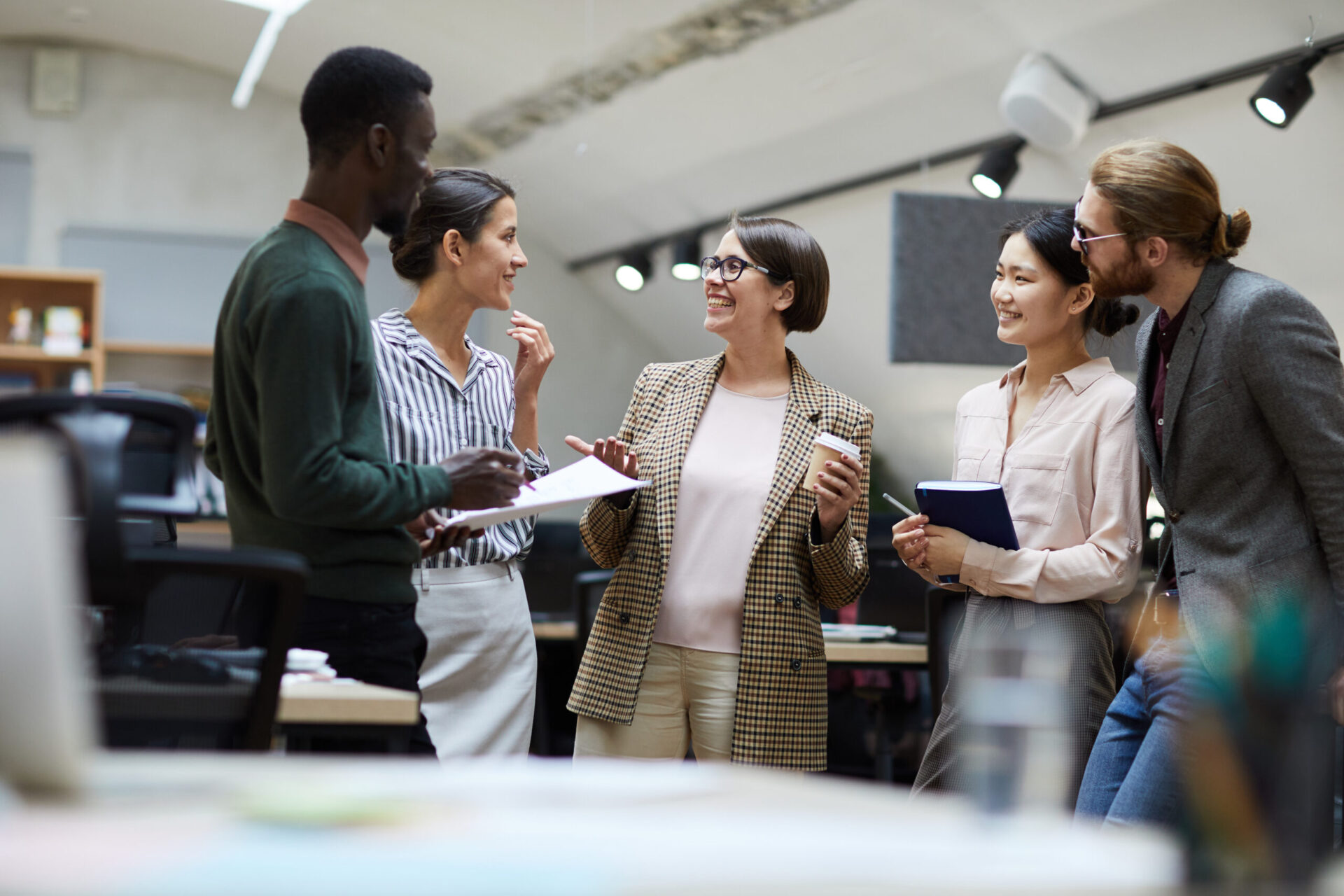 Multi-ethnic group of business people smiling cheerfully while chatting during coffee break in office, copy space