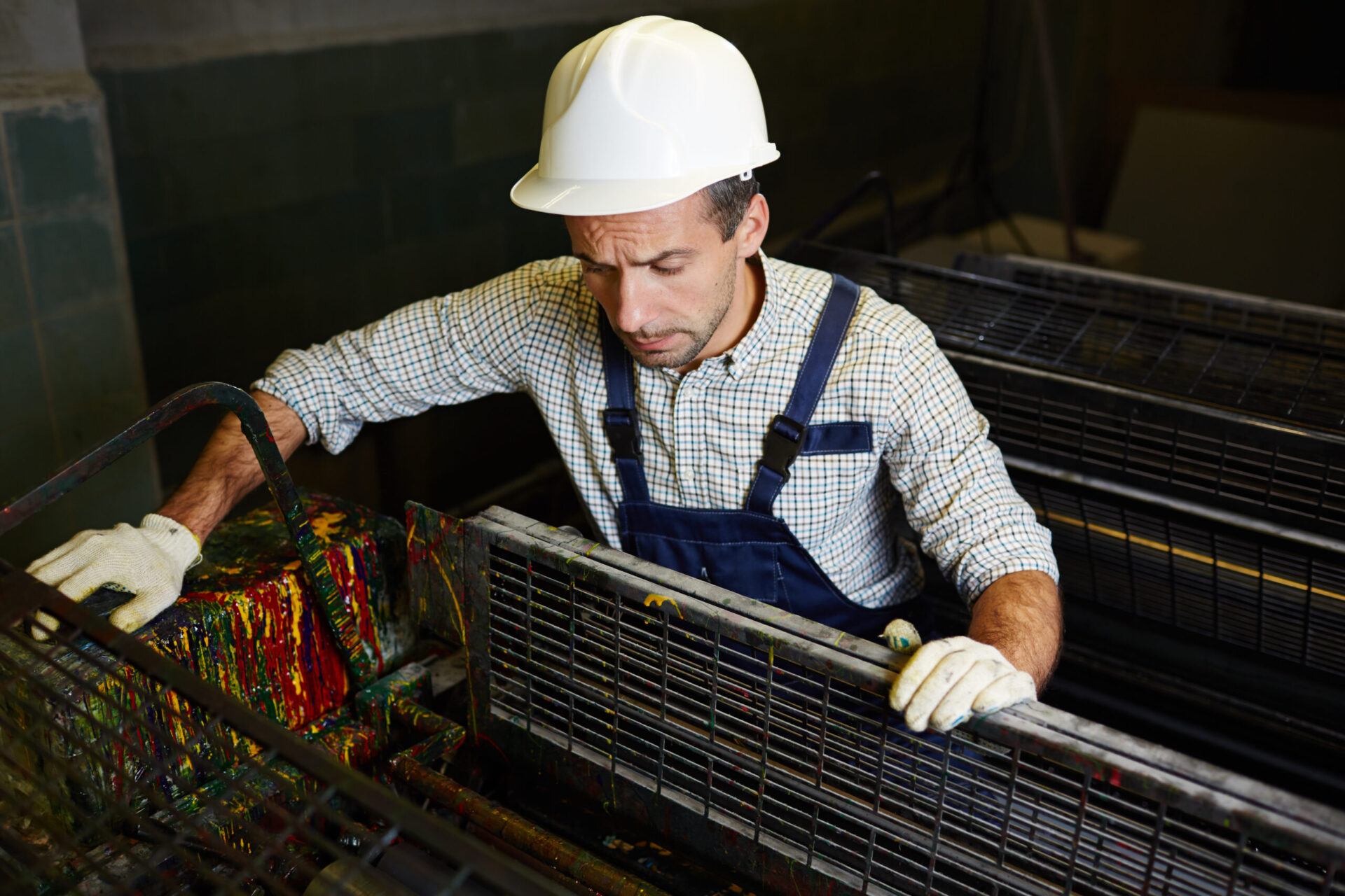 Factory worker opening cover of industrial machine to find out what the problem is