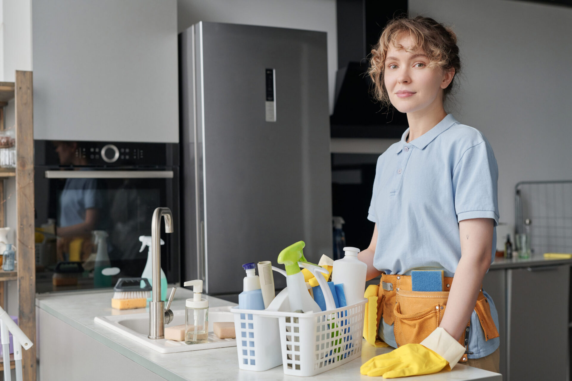 Portrait of professional cleaner looking at camera while using detergent in housework standing in the kitchen